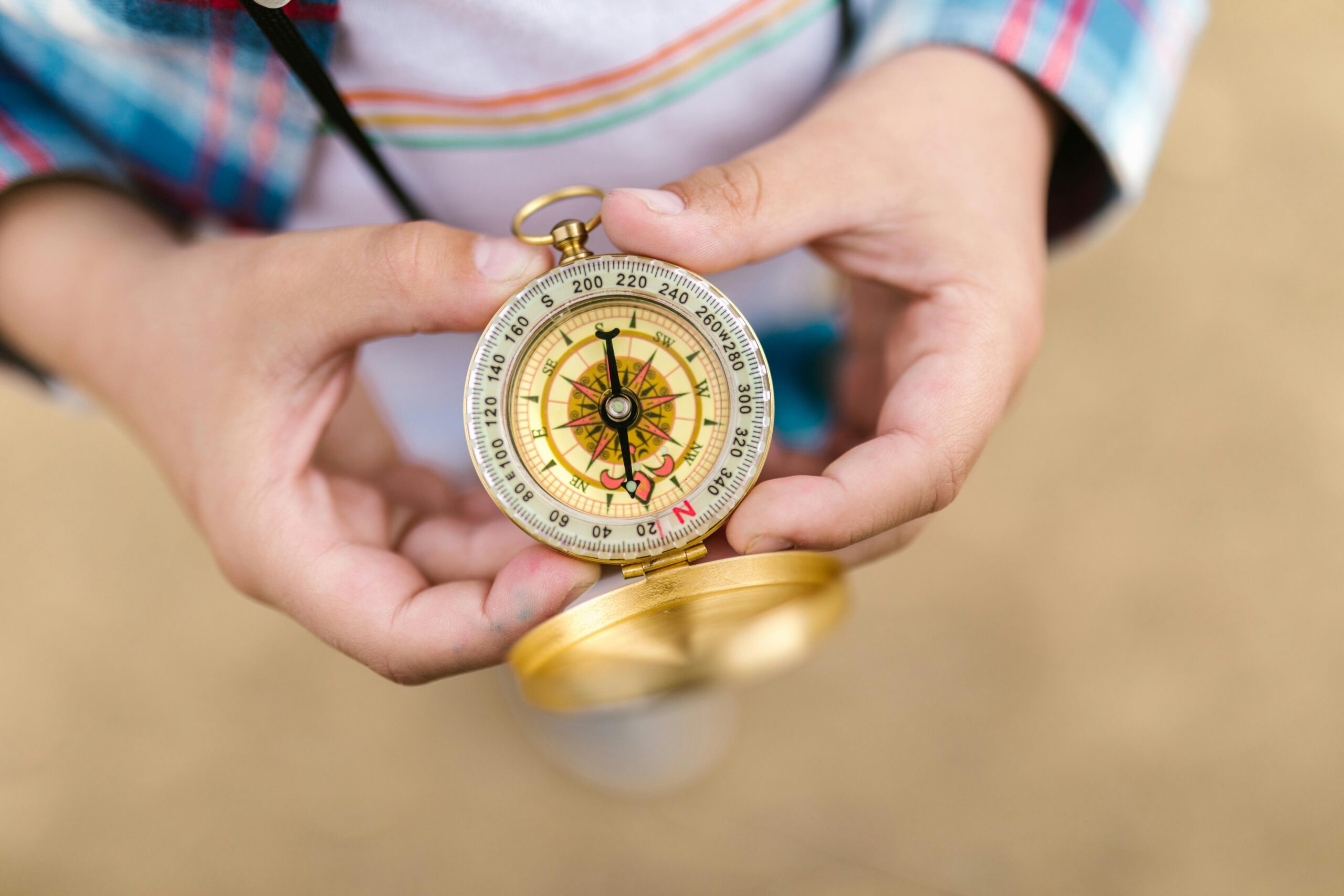 A detailed view of hands holding a vintage compass, suggesting exploration and guidance.